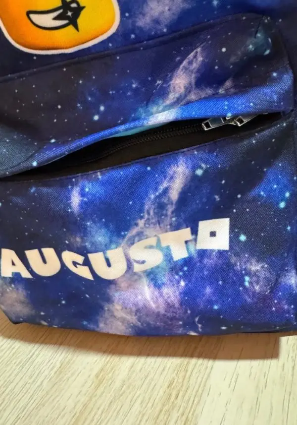 Mochila personalizable multiusos con bolsillo frontal abierto, cremallera negra y estampado espacial.