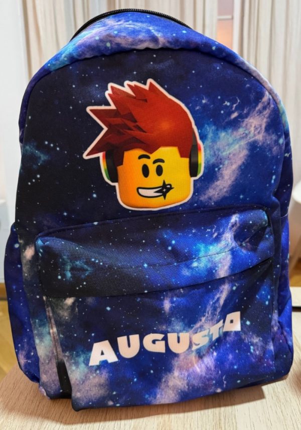 Mochila personalizada con estampado galáctico azul y nombre Augusto en el bolsillo frontal